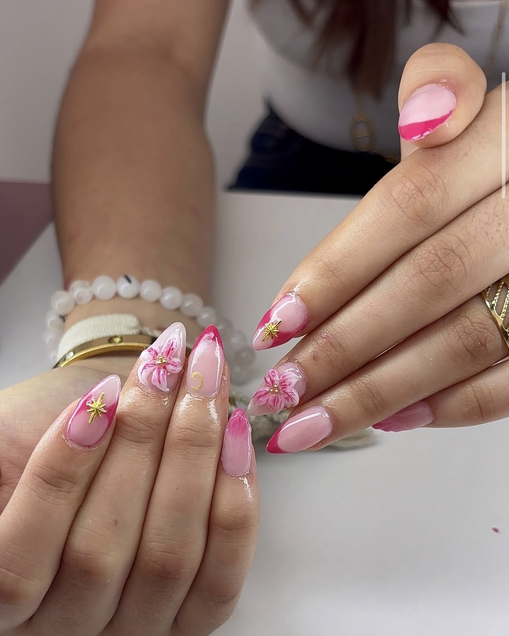 Ongles amande roses avec fleurs et étoiles dorées